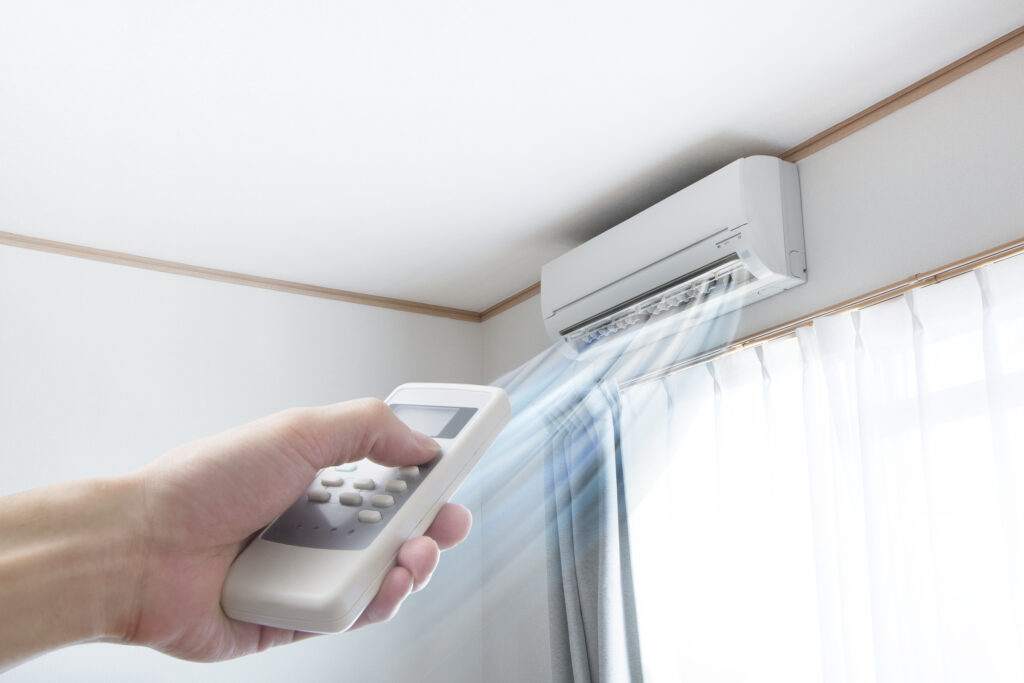 Hand pointing a remote at a wall-mounted ductless mini-split